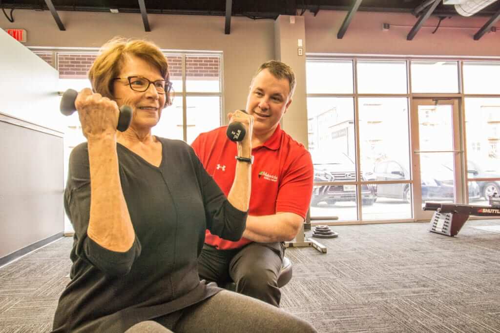 Geriatric Physical Therapist assists patient with exercise