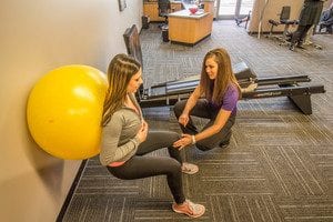 Makovicka physical therapist assists patient in wall sit stability ball exercise