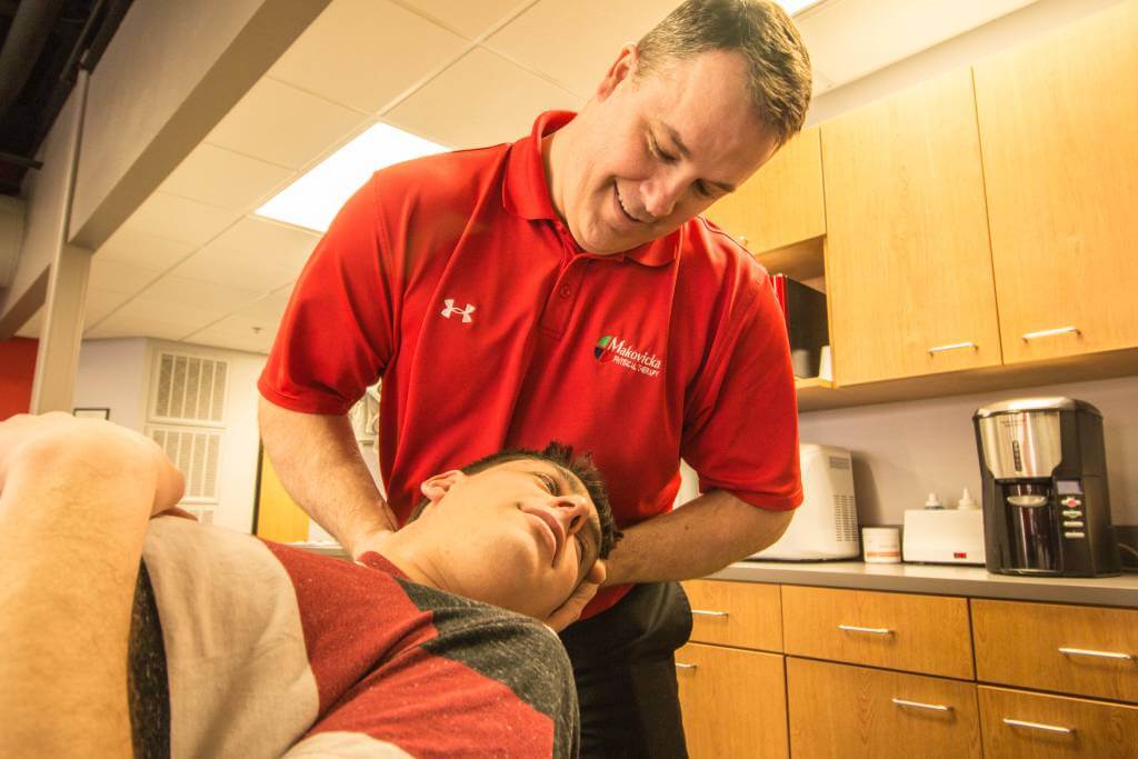 Makovicka physical therapist stretches patient's neck during therapy session