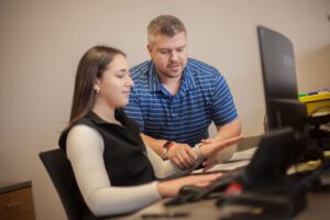 Occupational Health Coordinator, Trey Fox, works with employee on proper ergonomics at a workstation